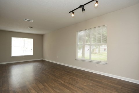 A room with wooden floors and a window with blinds.