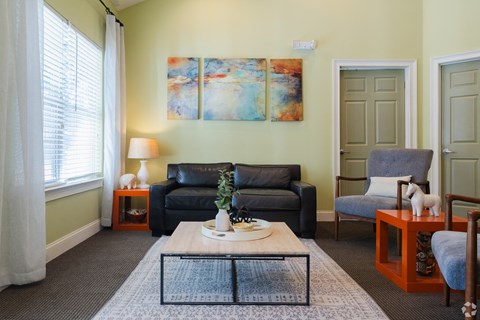 A living room with a grey couch, a blue chair, and a painting on the wall.