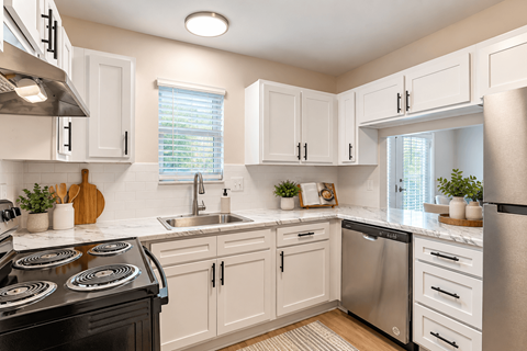 A kitchen with white cabinets and a black stove top.