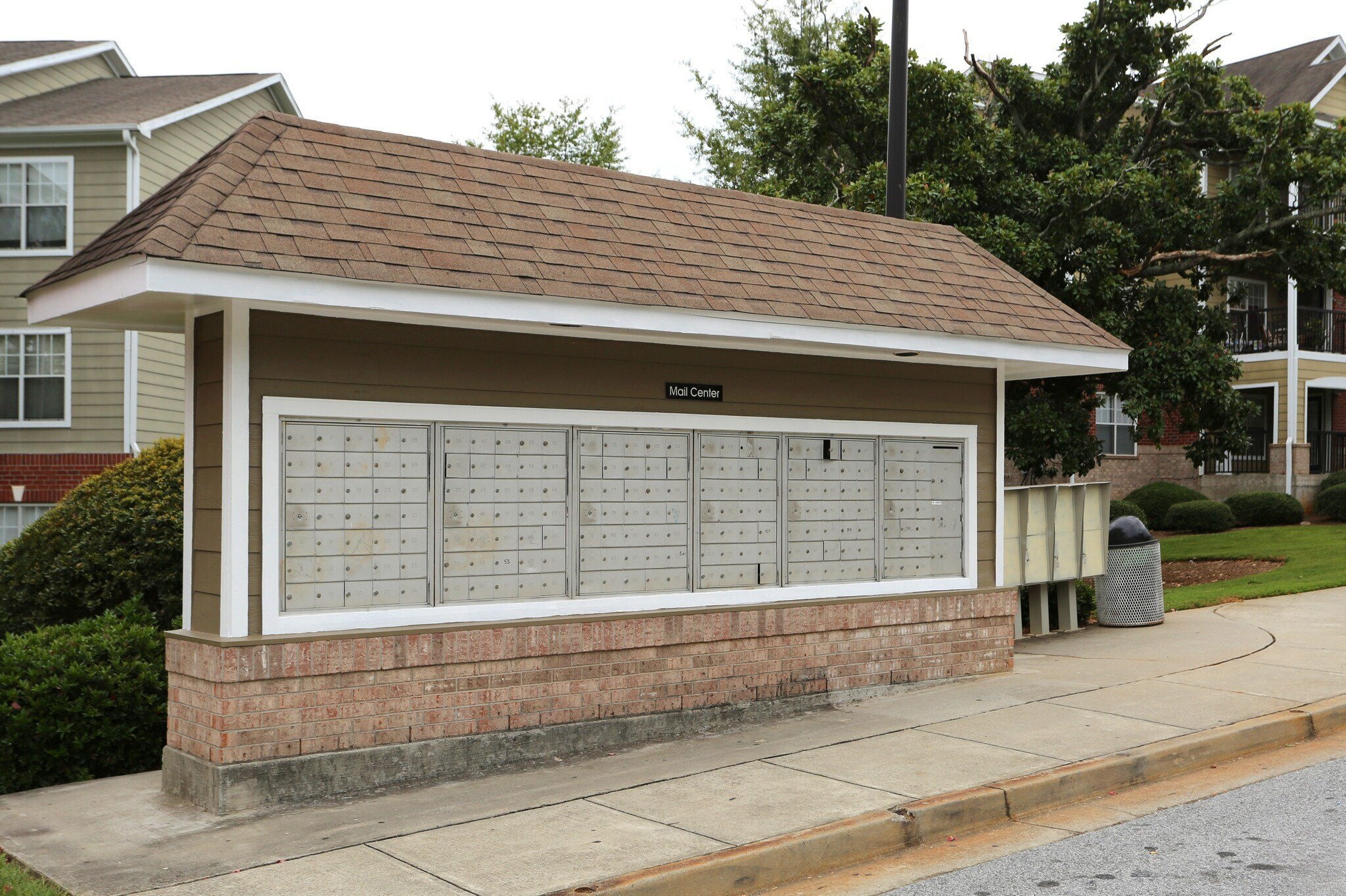 A small building with a brown roof and a sign that says "Bellhop's Den" is in front of a house.