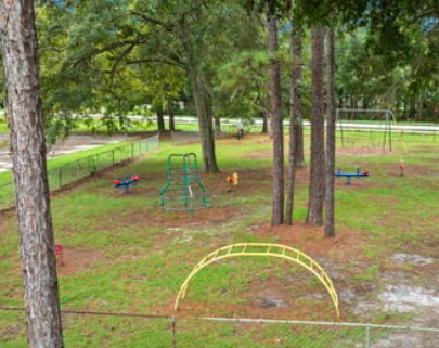 A playground with a yellow arch and a green swing set.