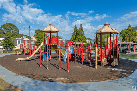 A playground with a red slide and two red towers.