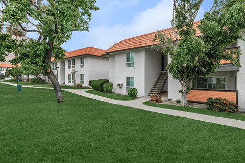 A white building with a red roof is surrounded by a green lawn.