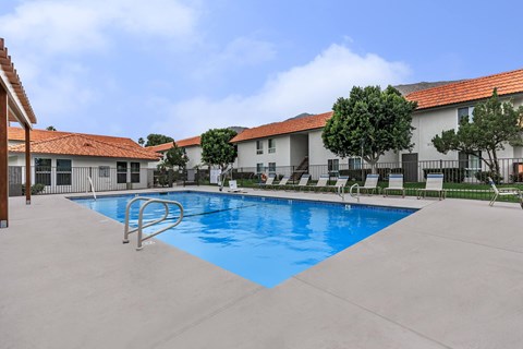 A swimming pool in front of a building with a red roof.