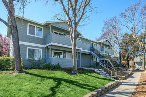 A grey two-story house with a green lawn in front.