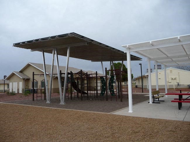 a playground with a swing set and a picnic table under awning
