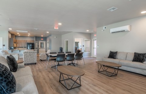 A spacious living room with a grey sofa, a wooden coffee table, and a kitchen area in the background.
