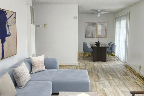 A living room with a grey couch and a painting on the wall.