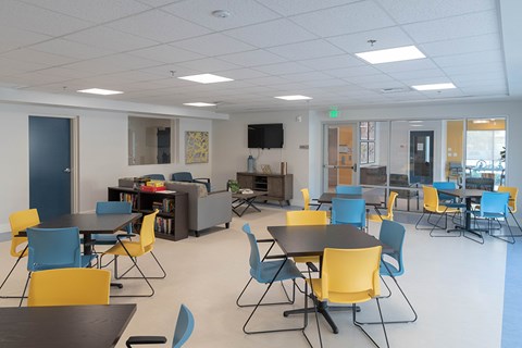 A room with tables and chairs and a television.