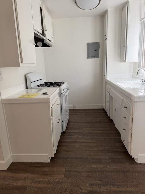 A small white kitchen with a stove and sink.