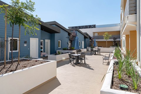 A courtyard with tables and chairs surrounded by buildings.