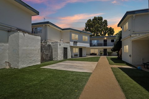 A pathway leads through a grassy area between two rows of houses.