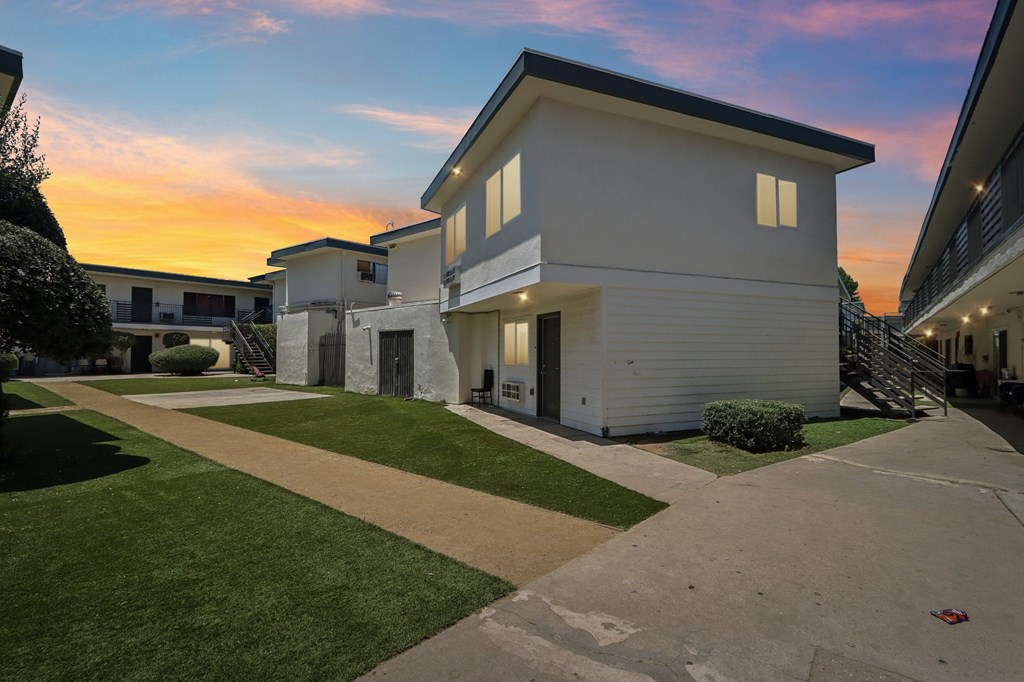 A row of white houses with a sunset in the background.