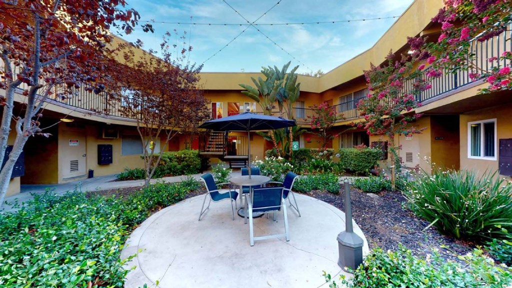 a patio with a table and chairs in a courtyard at The Marquee Apartments, North Hollywood, CA