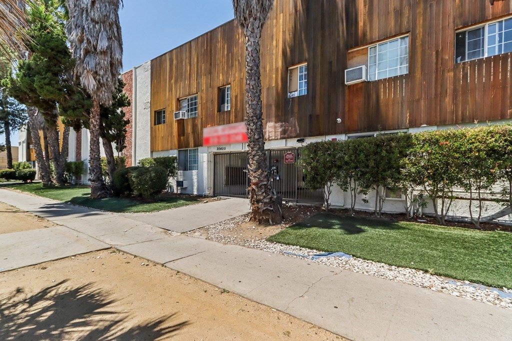 A building with a red awning is surrounded by trees and shrubs.
