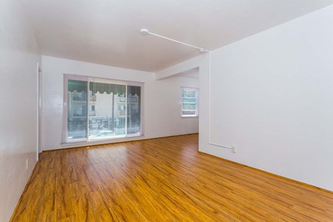 an empty living room with wood floors and a window