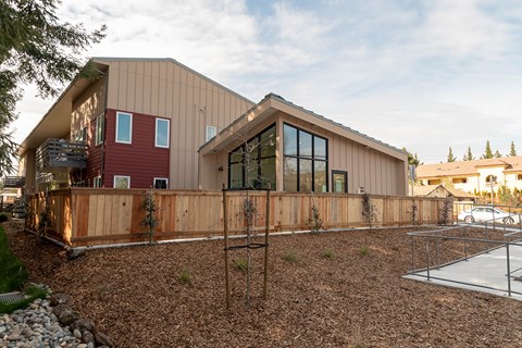 A modern house with a red section and a wooden fence.