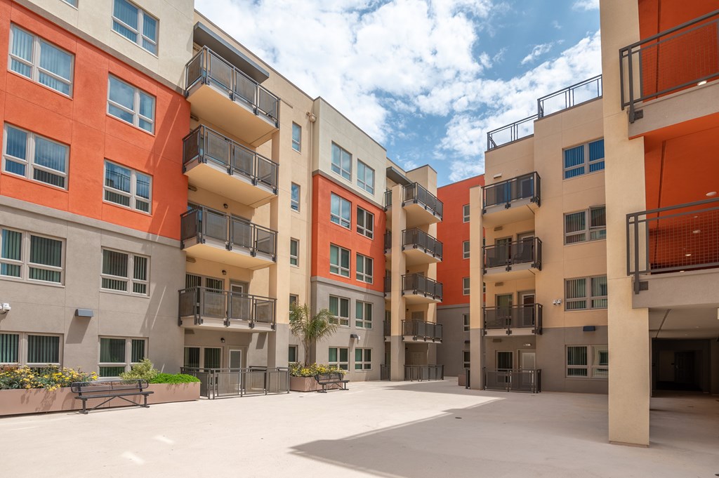A large open courtyard surrounded by orange and beige buildings with balconies.