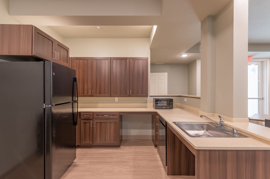 A modern kitchen with dark wood cabinets and a black refrigerator.
