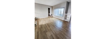 A room with wooden flooring and a window with blinds.