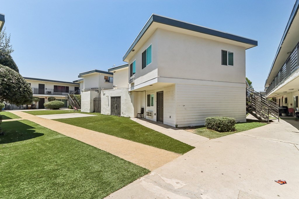 A white house with a black roof and a green lawn in front.
