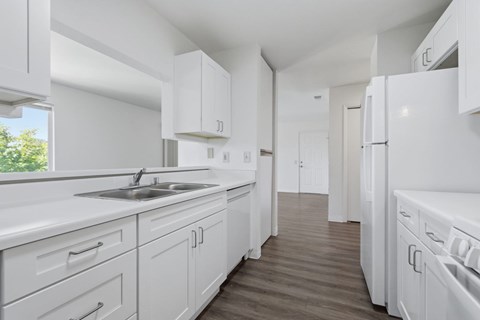 A white kitchen with a sink and a refrigerator.