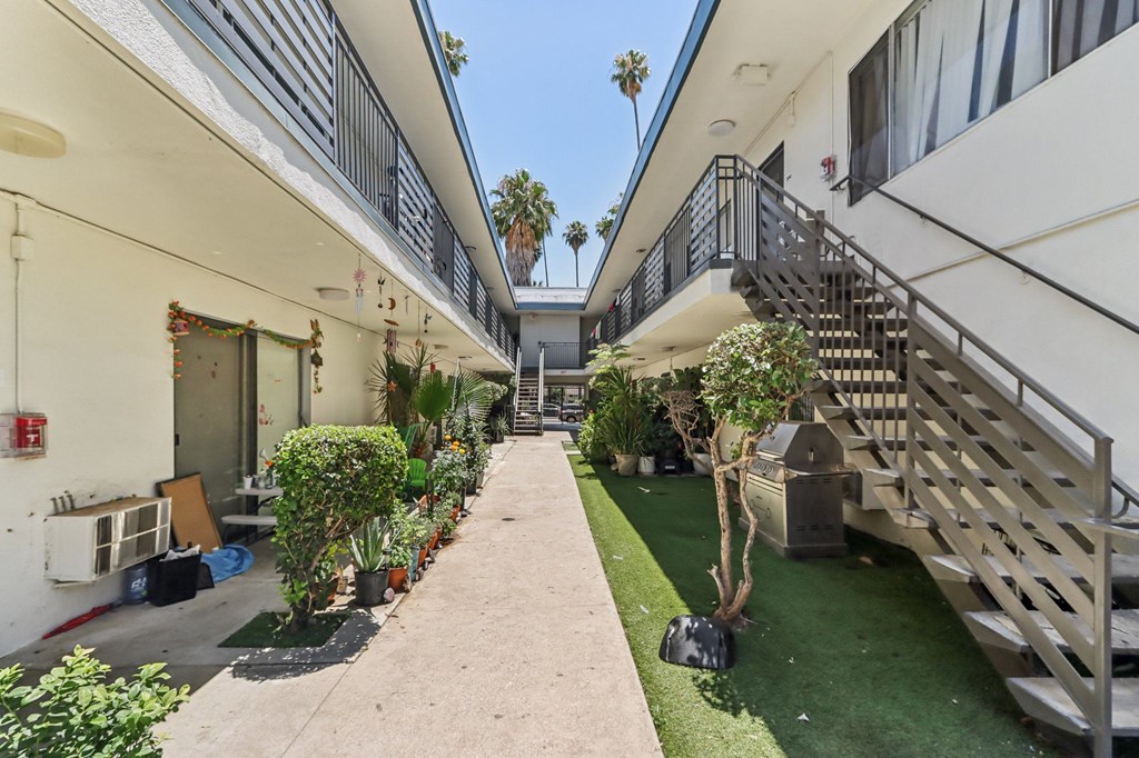A long, narrow courtyard between two buildings with a metal staircase on the right.