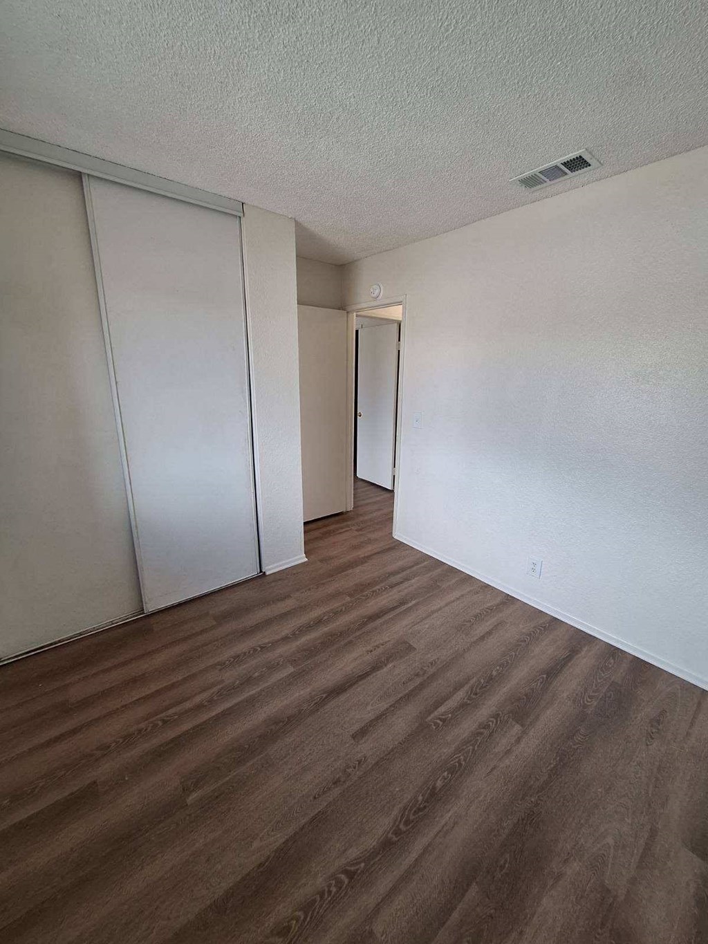 an empty living room with white walls and wood floors