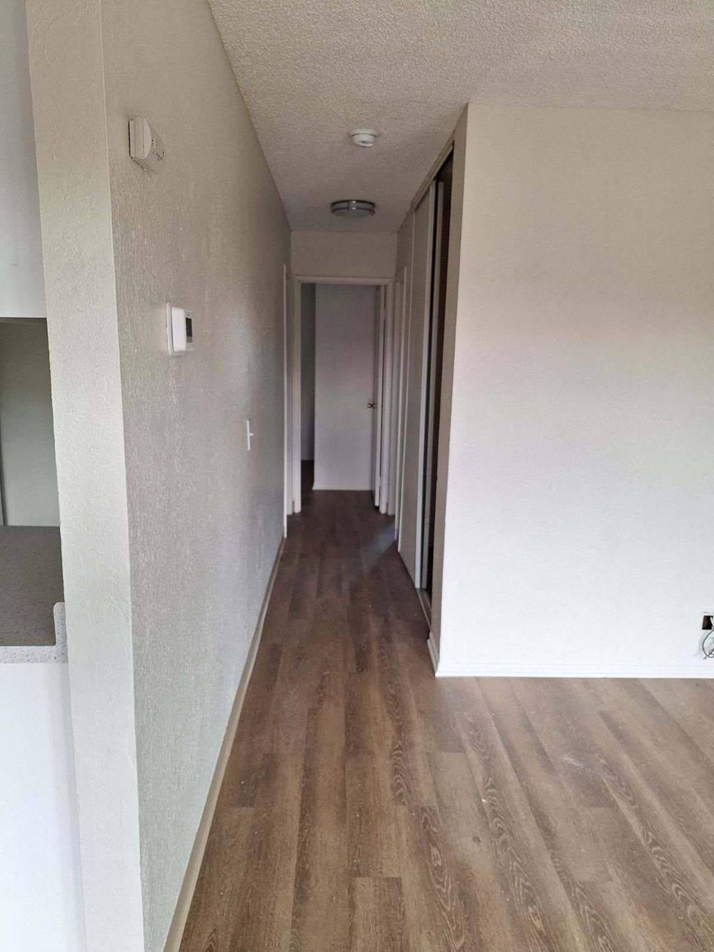 a long hallway with white walls and wood floors