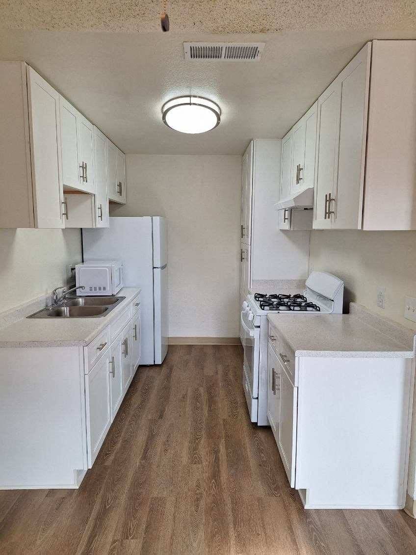 an empty kitchen with white cabinets and white appliances