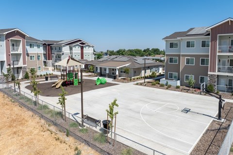 A basketball court is surrounded by apartment buildings.