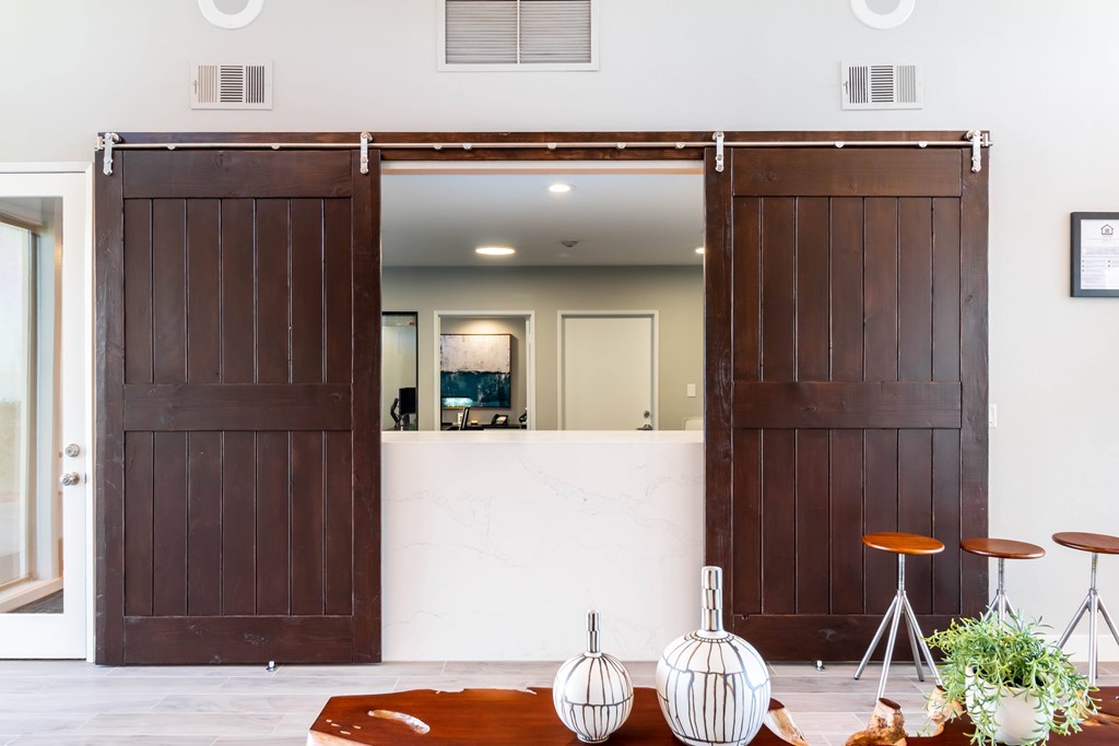 A white room with a brown door and a white table with a plant on it. at Chaparral Apartments, Palmdale, CA