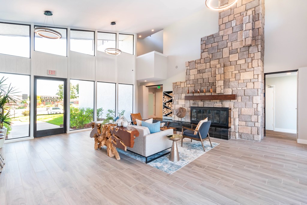 A living room with a stone fireplace and a couch at Chaparral Apartments, California, 93551