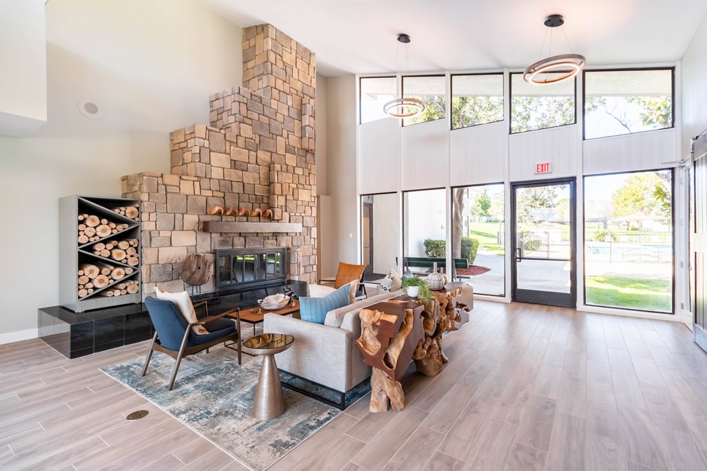 A modern living room with a stone fireplace and a blue rug at Chaparral Apartments, Palmdale, California