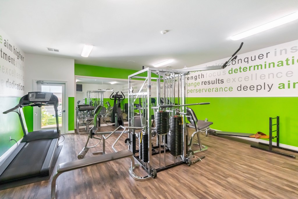 A gym with a green wall and a variety of equipment. at Chaparral Apartments, California