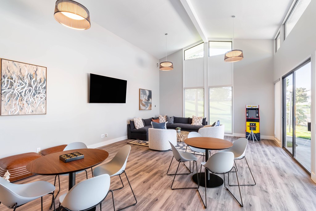 A modern living room with a wooden table and white chairs at Chaparral Apartments, Palmdale, CA, 93551