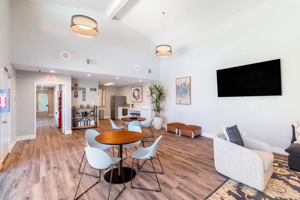 A living room with a TV on the wall and a dining table with chairs at Chaparral Apartments, Palmdale