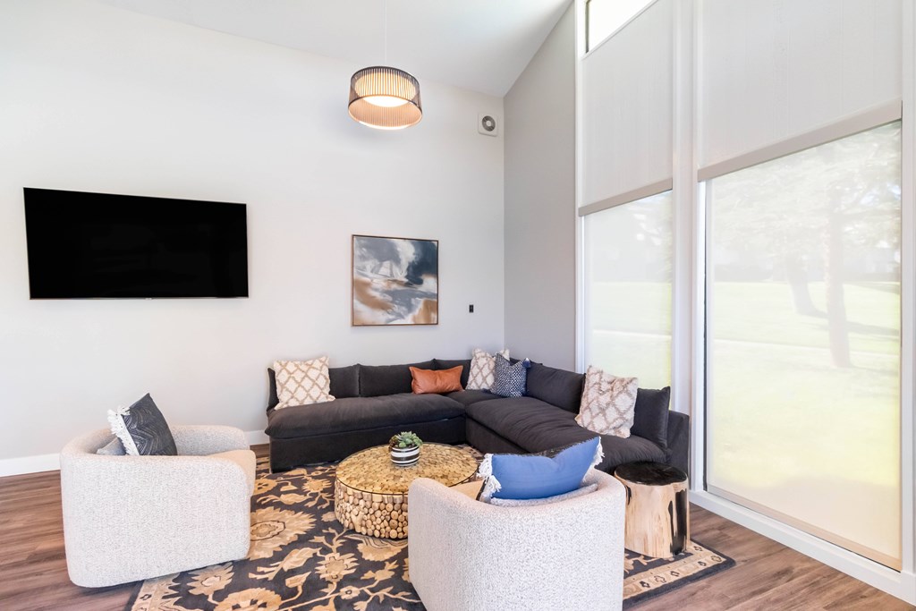 A living room with a black couch and a television on the wall. at Chaparral Apartments, California