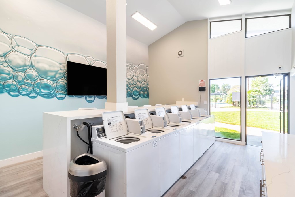 A row of washing machines are lined up in a room. at Chaparral Apartments, California, 93551
