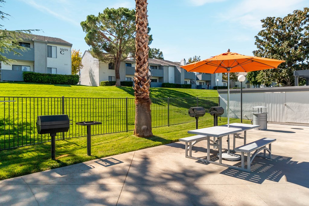 A bright orange umbrella is on a table outside a building at Chaparral Apartments, Palmdale 93551