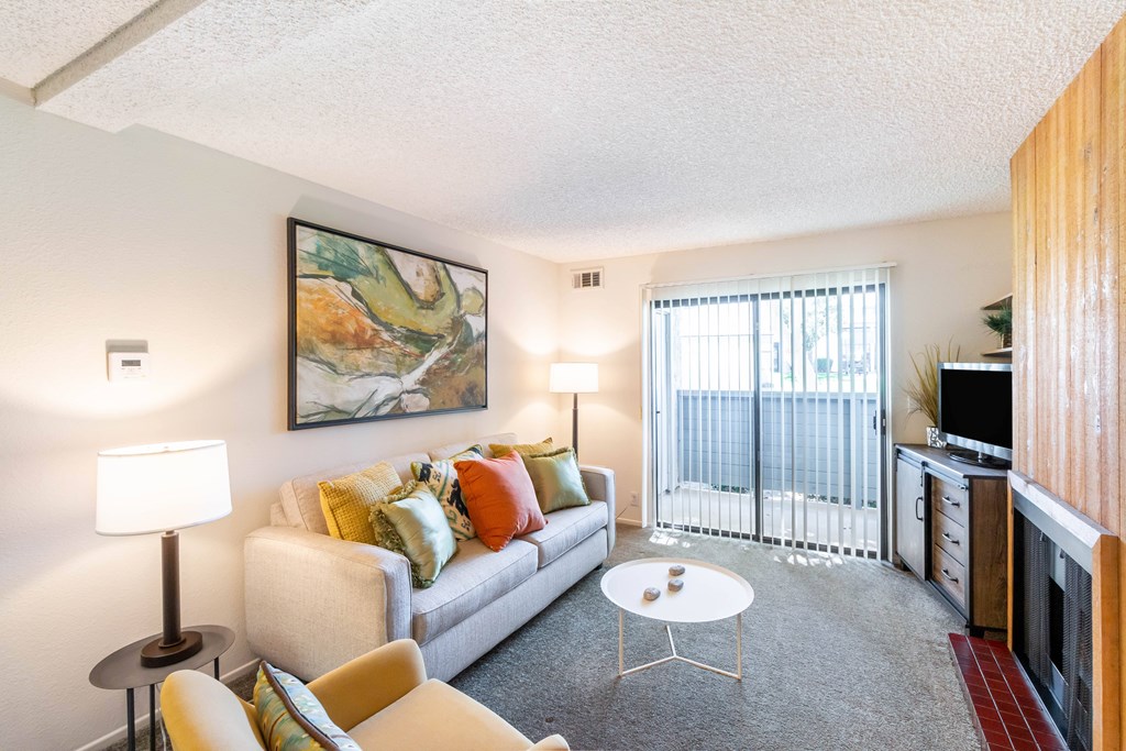 A living room with a couch, chairs, and a painting on the wall at Chaparral Apartments, California