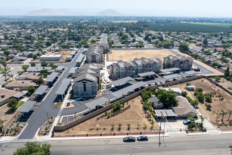 A large, modern building complex is surrounded by a parking lot and other buildings.