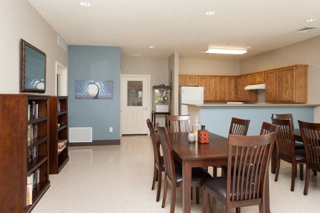 a dining area with a table and chairs and a kitchen in the background