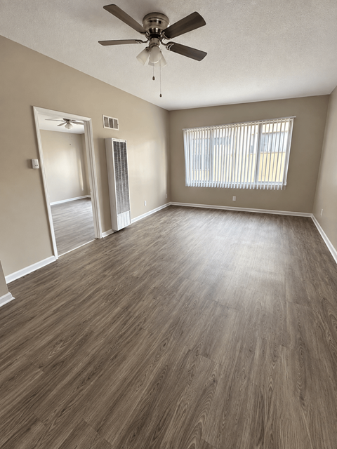 A room with a ceiling fan and wooden flooring.