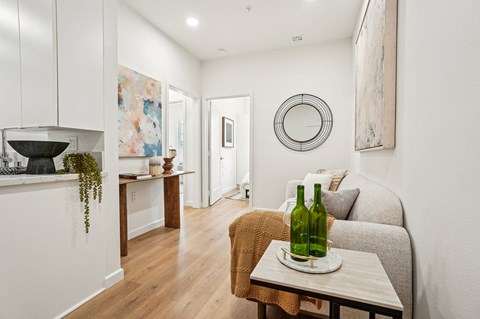 A living room with a grey couch and a green bottle on a table.