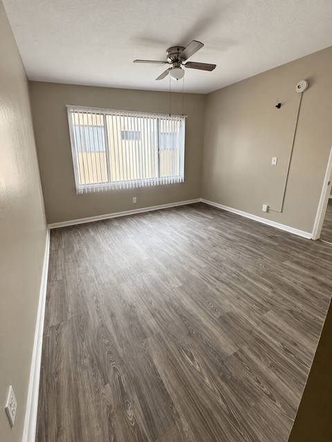 A room with a ceiling fan and a window with blinds.
