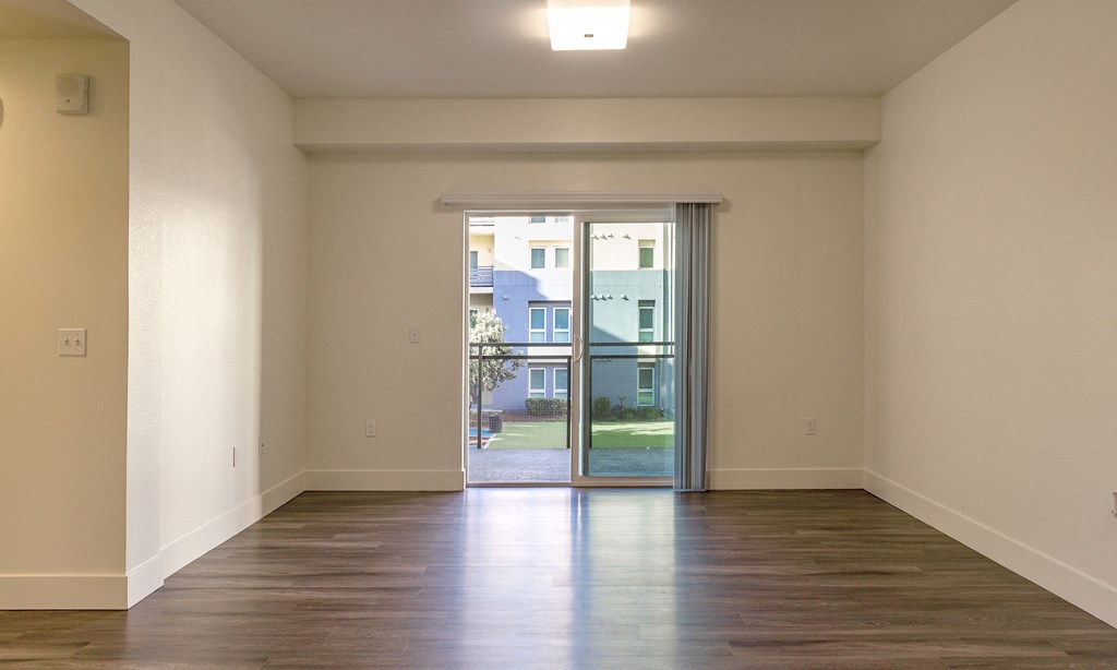 an empty living room with a door to a balcony