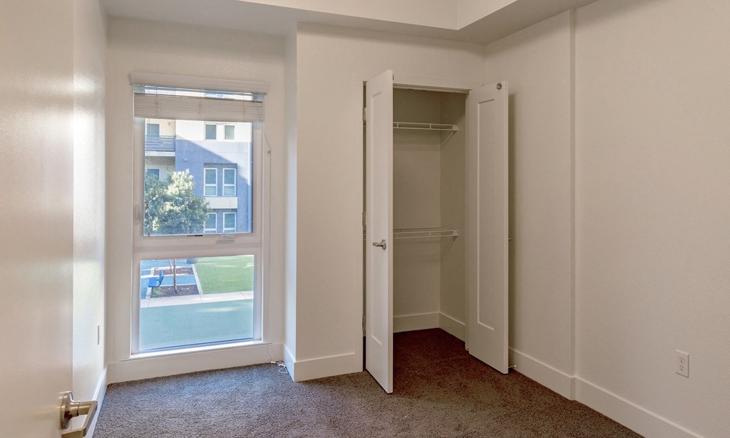 an empty bedroom with a closet and a window