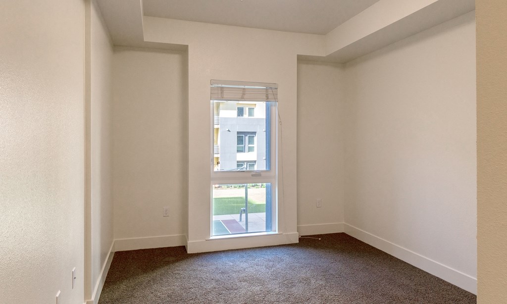 an empty living room with a window and carpeting