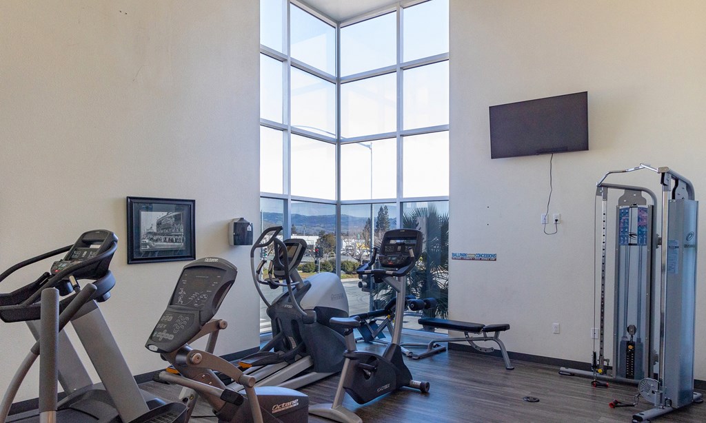 a gym with cardio equipment and a large window